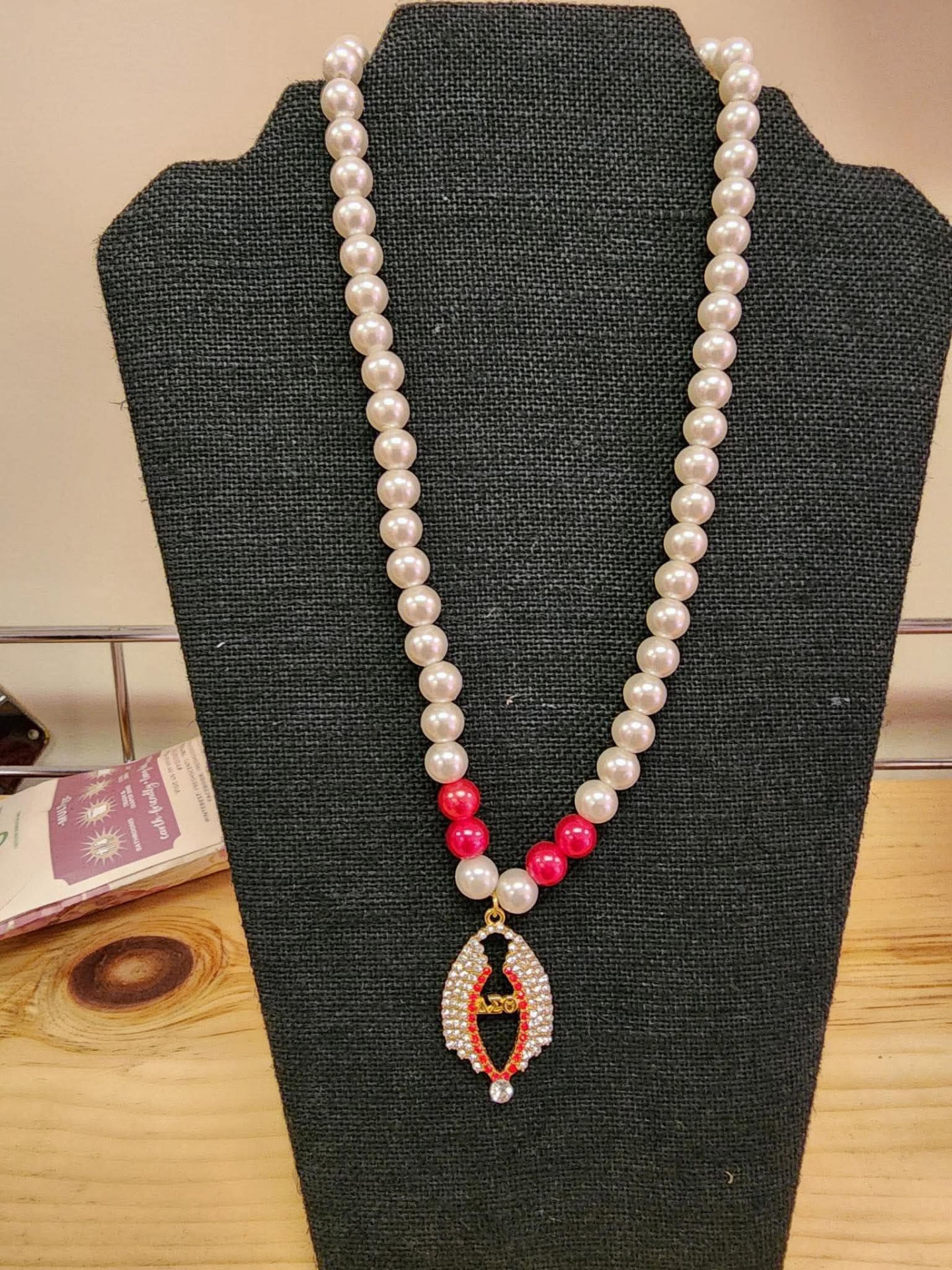 Ivory pearl necklace with crimson accent beads and a sparkling wishbone-inspired pendant with Delta detailing