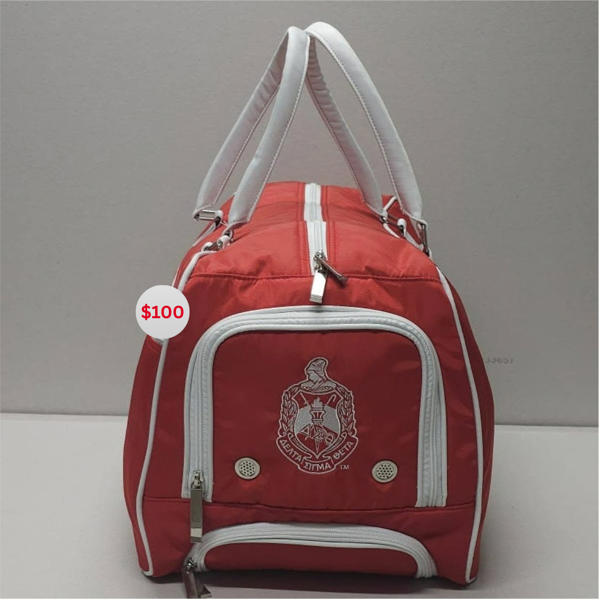 Red Delta Sigma Theta trolley travel bag with white piping and trim, sturdy handles, and embroidered crest